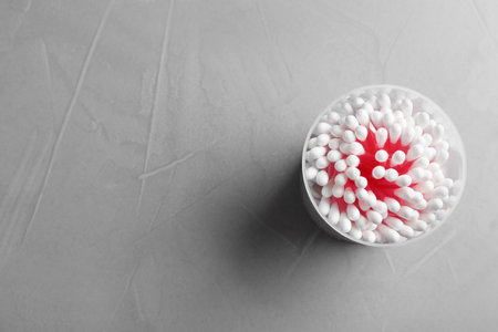 Plastic container with cotton swabs on gray background, top view. Space for textの写真素材