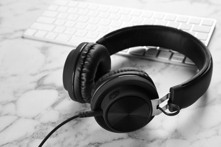 Modern headphones and computer keyboard on tableの写真素材