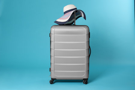 Stylish suitcase with hat on color backgroundの写真素材