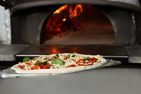 Putting traditional Italian pizza into oven in restaurant kitchenの写真素材