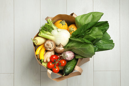 Paper bag full of fresh vegetables on light background, top viewの写真素材