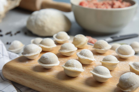 Board with raw dumplings on table, closeup. Process of cookingの写真素材