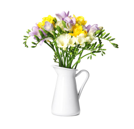Bouquet of fresh freesia flowers in jug isolated on whiteの写真素材