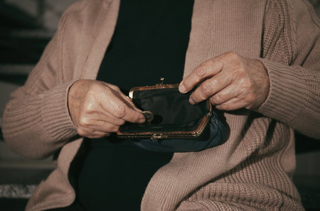 Poor senior woman with empty wallet and coin indoors, closeupの写真素材