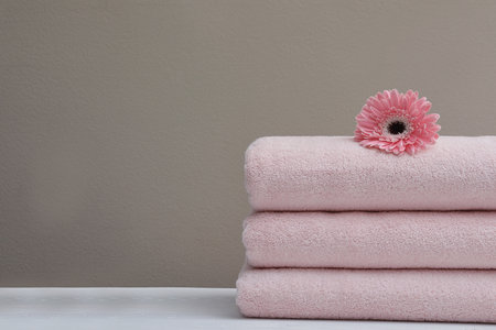 Stack of fresh towels with flower on table. Space for textの写真素材
