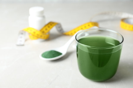 Glass of spirulina drink and powder on table, space for textの写真素材
