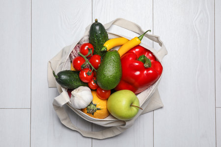Bag full of fresh vegetables and fruits on light background, top viewの写真素材