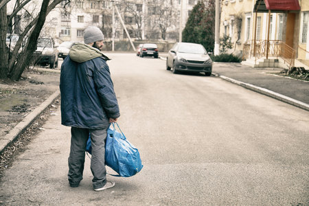 Poor homeless man with bag on city streetの素材 [FY310212033462]