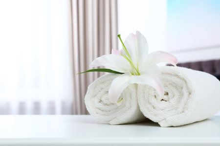 Rolled towels and flower on the table in the bedroom. Space for textの写真素材