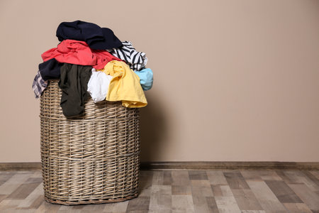 Laundry basket with dirty clothes on floor indoors. Space for textの写真素材