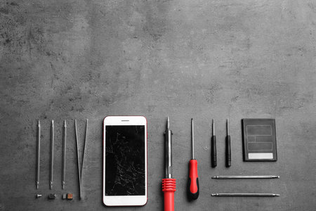 Broken mobile phone and repair tools on table, flat lay. Space for textの写真素材