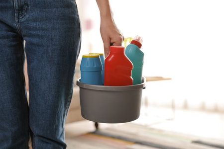 Woman with basket of professional cleaning products indoors, closeup. Space for textの写真素材