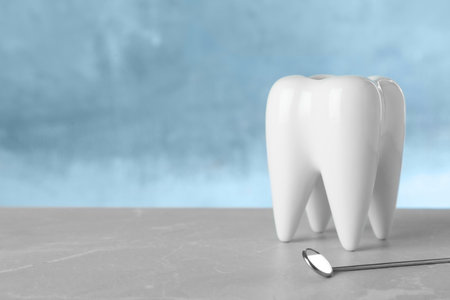 Dentist mirror and tooth shaped holder on table. Space for textの写真素材