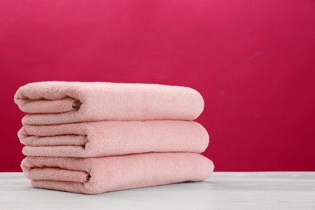 Stack of soft clean towels on table against color background. Space for textの写真素材