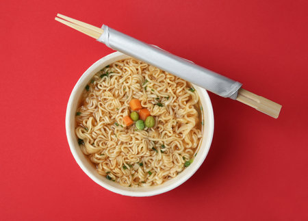 Cup of cooked instant noodles with chopsticks on color background, top viewの写真素材
