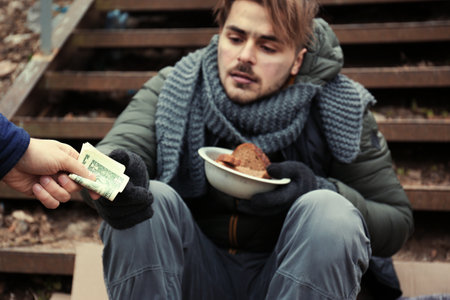 Poor young man begging for money on stairs outdoors, closeupの写真素材