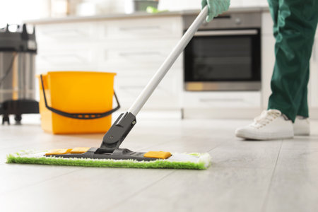 Professional janitor cleaning floor with mop in kitchen, closeup. Space for textの写真素材