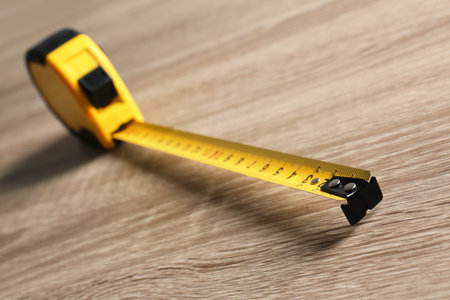 Metal measuring tape on wooden background. construction toolの写真素材
