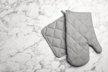 Protective oven glove and potholder on marble table, top view with space for textの写真素材