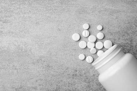 Bottle with different pills on gray background, flat lay. Space for textの写真素材