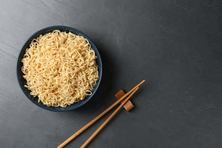 Bowl with tasty instant noodles and chopsticks on table, flat lay. Space for textの写真素材