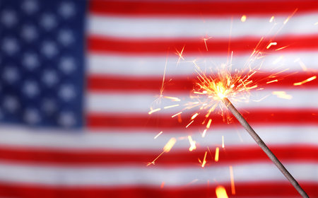 Burning sparkler against USA flag, closeup with space for text. Happy Independence Dayの写真素材