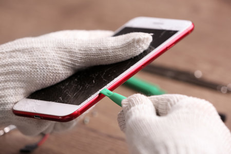 Technician fixing mobile phone at table, closeup. device repair serviceの写真素材