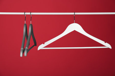 Empty clothes hangers on metal rail against color background. Space for textの写真素材
