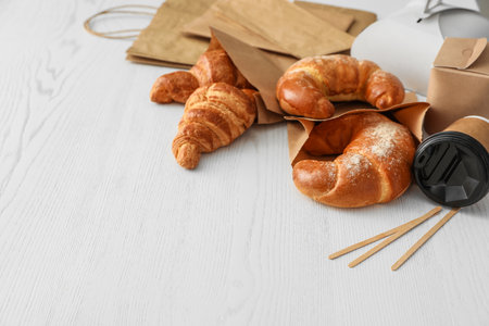 Paper bags with pastry and takeaway food on light table. Space for textの写真素材