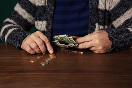 Poor senior woman with money at table, closeupの写真素材