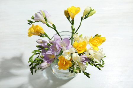 Bouquet of fresh freesia flowers in vase on table, above viewの写真素材