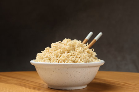 Bowl of hot noodles with chopsticks on table against gray backgroundの写真素材