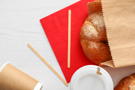 Flat lay composition with paper bag and pastry on light wooden background. space for designの写真素材