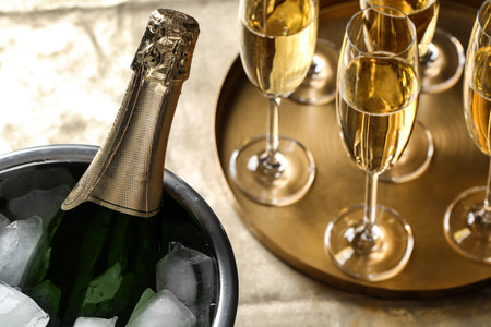 Bottle of champagne in bucket with ice and glasses on table, closeup. Space for textの写真素材