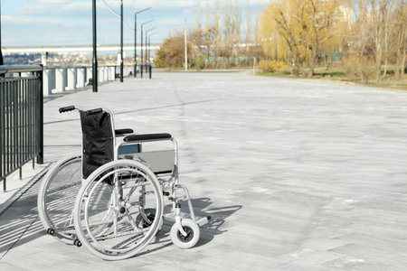 Empty wheelchair on embankment on sunny day. Space for textの写真素材