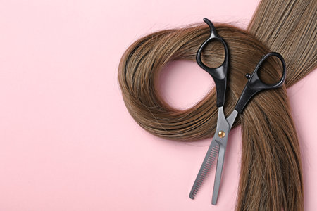 Flat lay composition with brown hair, thinning scissors and space for text on color background. hairdresser serviceの写真素材