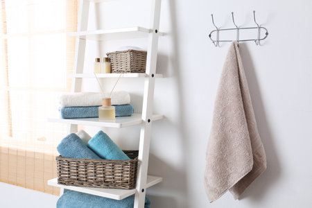 Shelving unit and rack with clean towels and toiletries near white wallの写真素材