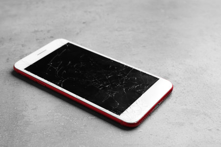 Modern smartphone with broken display on table. device repair serviceの写真素材