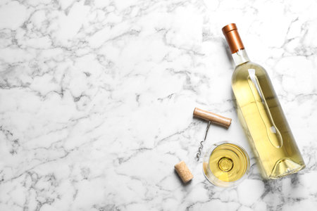 Glass and bottle with white wine on marble background, flat lay. Space for textの写真素材