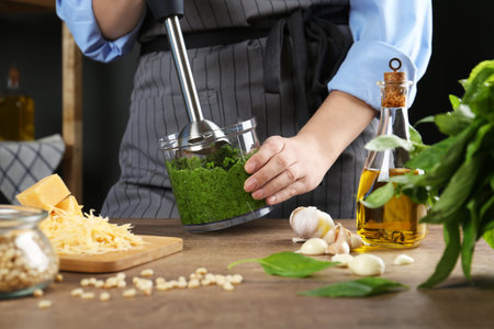 Woman blending pesto sauce in bowl at table, closeupの写真素材