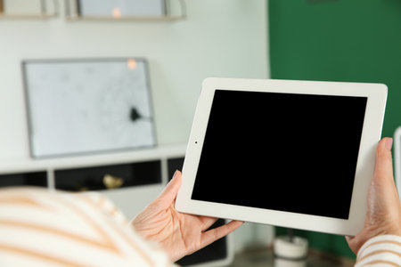 Woman using video chat on tablet at home, closeup. Space for text