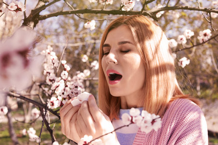 Woman suffering from seasonal allergy outdoors on sunny day