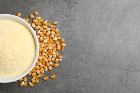 Bowl with corn flour and kernels on gray background, top view. Space for textの写真素材