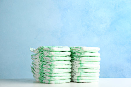 Stacks of diapers on table against color background, space for text. baby accessoriesの写真素材