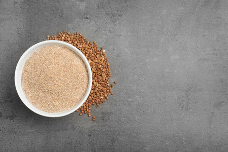 Bowl with buckwheat flour and seeds on gray background, top view. Space for textの写真素材