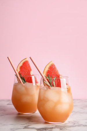 Glasses of grapefruit cocktails on table against color background. Space for textの写真素材