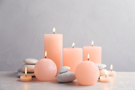 Beautiful composition with candles on table against gray backgroundの写真素材