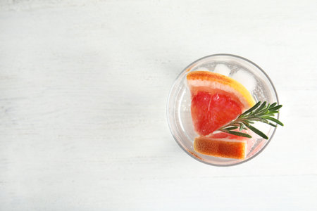 Glass of infused water with grapefruit slices on white table, top view. Space for textの写真素材
