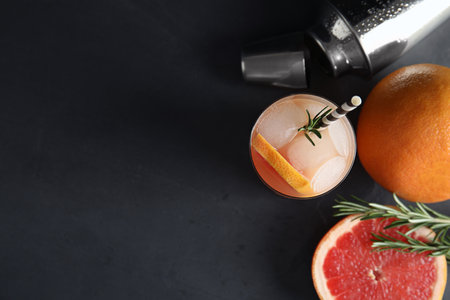 Flat lay composition with glass of grapefruit cocktail and space for text on dark tableの写真素材