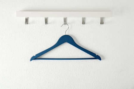 Rack with empty clothes hanger on light wall. Wardrobe accessory